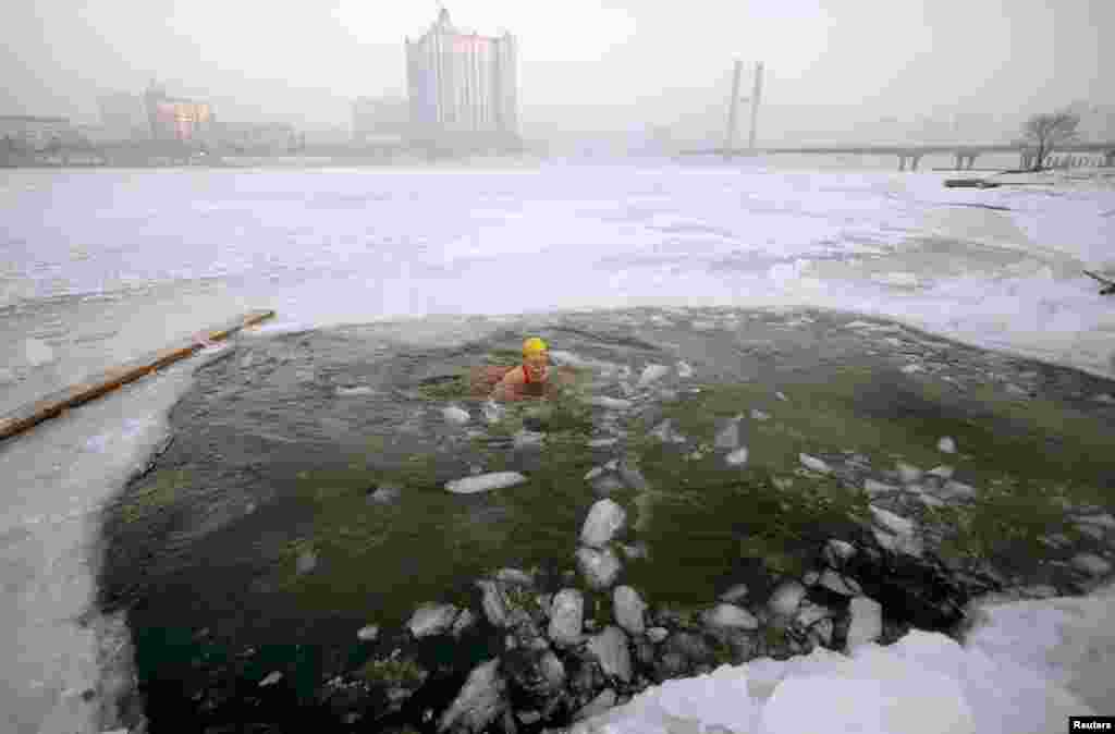 A woman swims in icy waters after breaking the ice of the frozen Songhua River in Jilin, Jilin province, China.