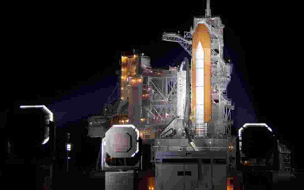 Las luces iluminan el transbordador espacial Discovery, en la plataforma de lanzamiento, donde se encuentran las estructuras de rotación.