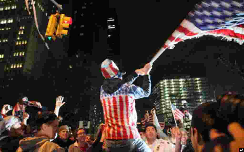 Perched on another's shoulders, Ryan Burtchell, of the Brooklyn borough of New York, center, waves an American flag over the crowd as they respond to the news of Osama Bin Laden's death, May 2, 2011