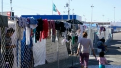 Migrantes caminan junto a la cerca de un campamento improvisado que bloquea la entrada a un cruce peatonal a Estados Unidos (arriba), el 8 de noviembre de 2021, en Tijuana, México.
