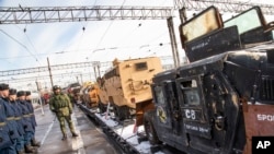 Russian soldiers stand next to a U.S. made armored personnel carrier, right, standing aboard a train that has begun a journey throughout Russia to display war trophies taken by military engineers in Syria, including defused explosives in Moscow, Russia, Saturday, Feb. 23, 2019. 