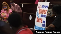 FILE - Activists wearing a rainbow mask sit at the Botswana High Court place placards as they listen to court proceeding, Oct. 12, 2021. 