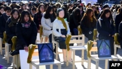 People sit around a statue of a "comfort woman" during an installation of empty chairs during a performance event, commemorating the death of eight former sex slaves this year, in Seoul, South Korea.