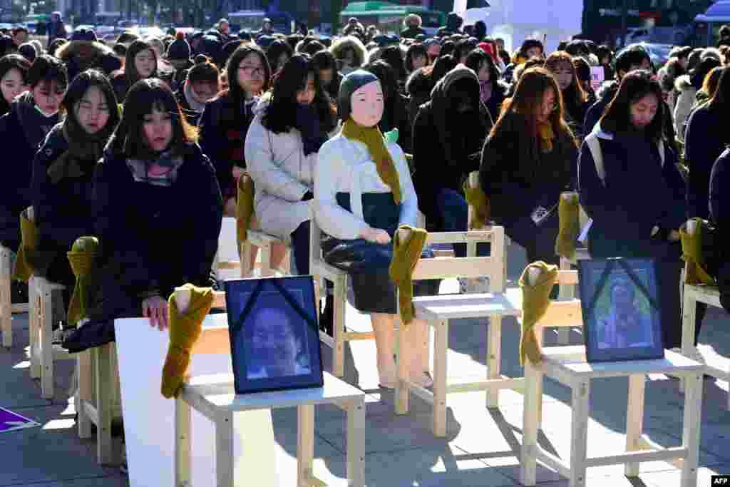 People sit around a statue of a "comfort woman" during an installation of empty chairs during a performance event, commemorating the death of eight former sex slaves this year, in Seoul, South Korea.