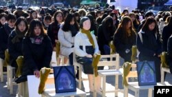 Kaum perempuan duduk di sekitar patung "perempuan penghibur," memperingati kematian delapan mantan budak seks tahun ini, di Seoul, Korea Selatan. (Foto: AFP)