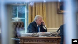 FILE - President Donald Trump speaks on the phone in the Oval Office at the White House in Washington, Jan. 28, 2017.