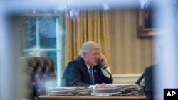 President Donald Trump speaks on the phone in the Oval Office at the White House in Washington, Jan. 28, 2017.