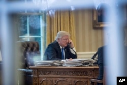 FILE - President Donald Trump speaks on the phone in the Oval Office at the White House in Washington, Jan. 28, 2017.