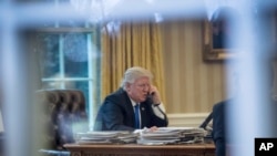 President Donald Trump speaks on the phone in the Oval Office at the White House in Washington, Jan. 28, 2017.