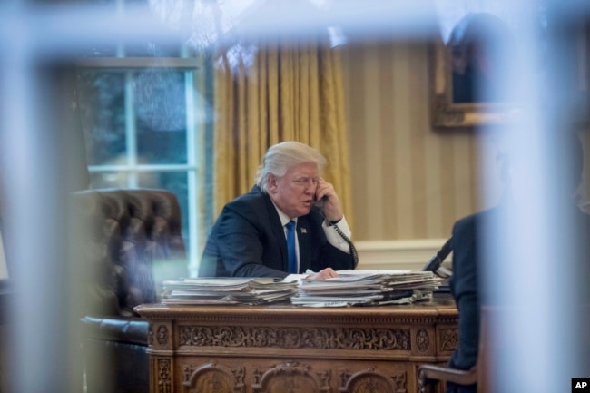 FILE - President Donald Trump speaks on the phone in the Oval Office at the White House in Washington, Jan. 28, 2017.