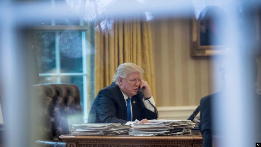 President Donald Trump speaks on the phone in the Oval Office at the White House in Washington, Jan. 28, 2017.