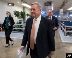 ສະມາຊິກສະພາສູງ ທ່ານດິກ ເດີບິນ ສັງກັດພັກເດໂມແຄຣັດ ຈາກລັດອີລລີນອຍ ຕິດຕາມດ້ວຍ ສະມາຊິກສະພາສູງ ທ່ານບັອບ ເມີນັນເດສ ສັງກັດພັກເດໂມແຄຣັດ ຈາກລັດນິວເຈີຊີ. D-N.J., walks to the Senate as Congress moves closer to the funding deadline to avoid a government shutdown, at the Capitol in Washington, Jan. 18, 2018.