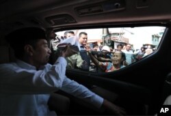 Presiden Joko Widodo membagikan buku kepada penduduk saat meninjau kawasan Tanah Tinggi, Jakarta, Jumat, 26 Juli 2019.