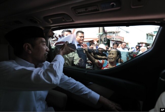 Presiden Joko Widodo membagikan buku kepada penduduk saat meninjau kawasan Tanah Tinggi, Jakarta, Jumat, 26 Juli 2019.