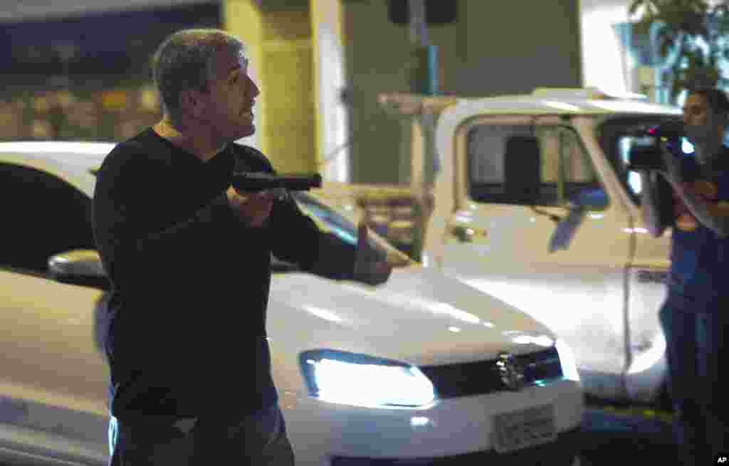 Um homem que se identificou como polícia aponta uma arma aos manifestantes anti-Mundial, que bloqueavam uma estrada que dá para o estádio do Maracanã, Rio de Janeiro, Brasil, Junho 15, 2014.