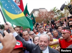 Former Brazilian President Luiz Inacio Lula da Silva carries a Brazilian flag as he arrives at Federal Justice, for a testimony in Curitiba, Brazil, May 10, 2017.