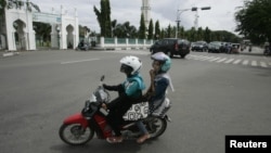 Dua perempuan Aceh berboncengan di atas sepeda motor dekat Mesjid Baiturrahman di Banda Aceh (3/1). (Reuters/Junaidi Hanafiah) 
