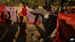 کابل میں اندرون ملک بے گھر ہونے والے پناہ گزینوں کا ایک کیمپ، ایک خاتوں اپنا بچہ گود لیے ہوئے ہے۔ 13 ستمبر 2021