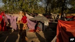 FILE - An internally displaced woman holds a child at a displaced persons camp in Kabul, Afghanistan, Sept. 13, 2021.