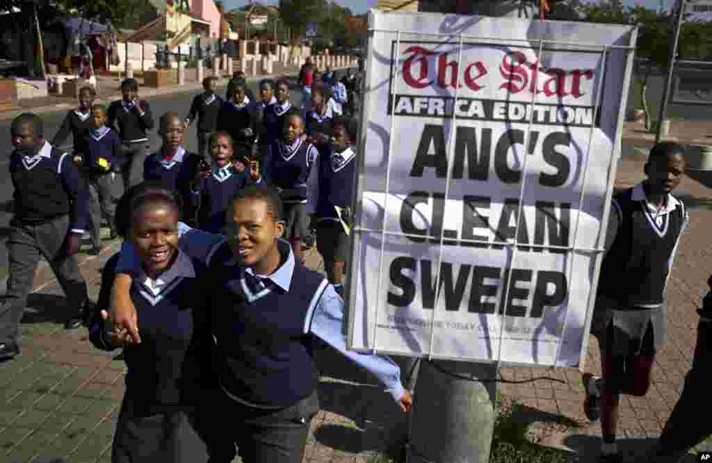 Schoolchildren walk past a newspaper placard reporting the election victory of Jacob Zuma&#39;s African National Congress (ANC) party, based on preliminary results, in the Soweto township of Johannesburg, South Africa, May 9, 2014.