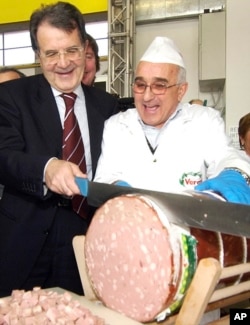 Romano Prodi slices a large Italian sausage while running for office in Bologna, Italy in 2006.