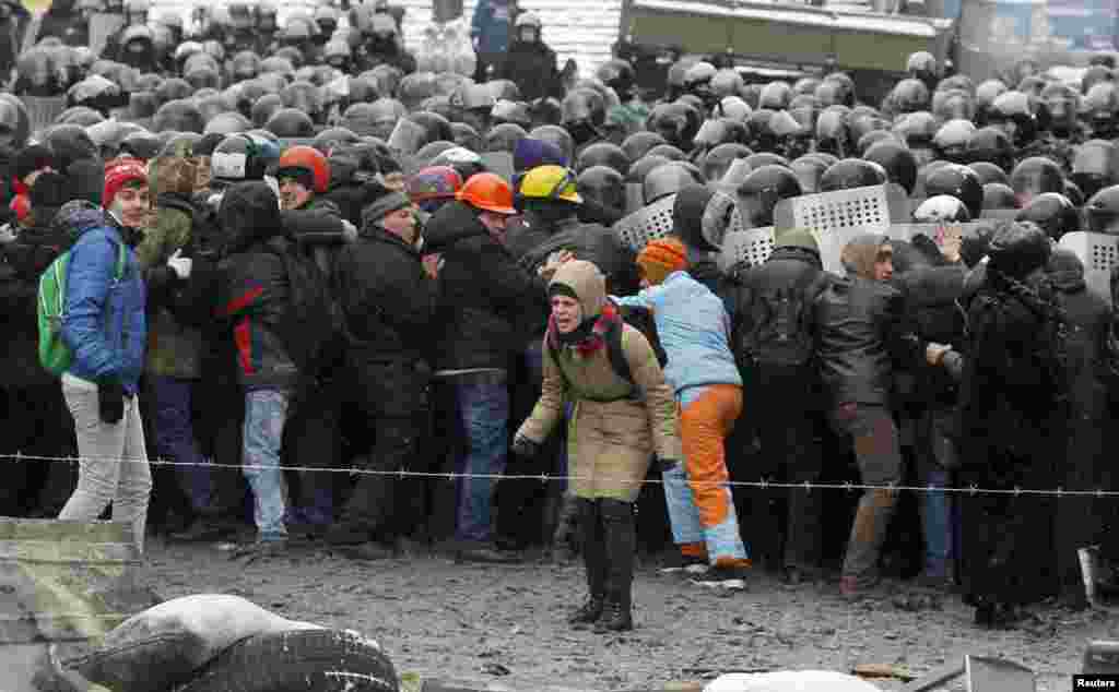 A woman reacts as riot police push pro-European protesters during a rally in Kyiv, Jan. 22, 2014.