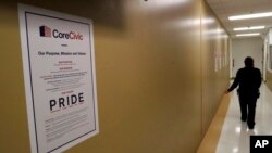 FILE - A guard passes a sign for CoreCivic at the Otay Mesa Detention Center, Aug. 23, 2017, in San Diego. The facility was at the center of the first big novel coronavirus outbreak at a U.S. immigration detention center in April 2020.
