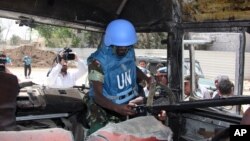 A U.N. observer takes pictures of a military bus that was damaged by a roadside bomb, at al-Bahdaliyah area, near Damascus, Syria, Wednesday, May 23, 2012. 