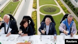 Guests enjoy a Dinner in the Sky meal on a platform suspended from a crane at a height of 40 metres (131 ft.) in front of the Arcades du Cinquantenaire in Brussels, June 8, 2017. 