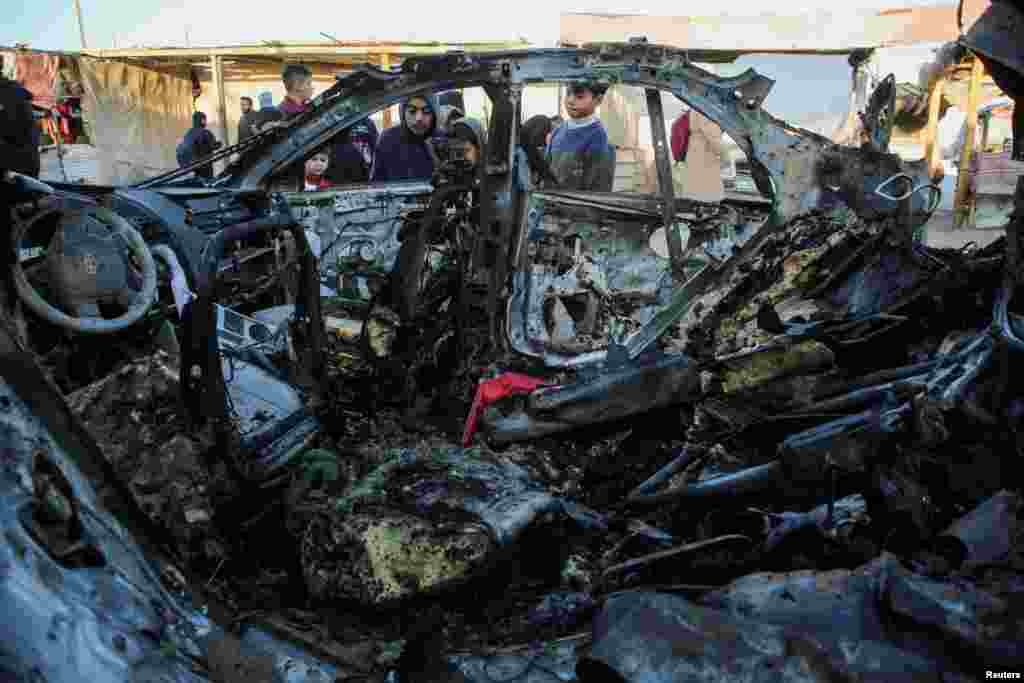 Palestinian children inspect the remains of a car in the aftermath of an Israeli strike, amid the Israel-Hamas conflict, in Khan Younis in the southern Gaza Strip.