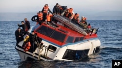 Refugees and migrants sit atop a heavily-listing small vessel as they try to travel from the Turkish coast to Skala Sykaminias on the northeastern Greek island of Lesbos, Oct. 30, 2015.