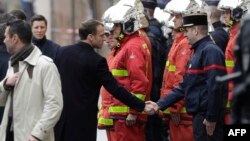 French President Emmanuel Macron (L) shakes hands with a firefighter during a visit in the streets of Paris on Dec. 2, 2018, a day after clashes during a protest of Yellow vests against rising oil prices and living costs. 