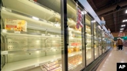 A shopper walks past partially empty frozen food coolers at a grocery in Cranberry Township, Pennsylvania, on Jan. 11, 2022. 