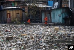 FILE - City workers remove garbage floating on the Negro River, which has a rising water level due to rain, in Manaus, Amazonas state, Brazil, June 6, 2022. (AP Photo/Edmar Barros, File)