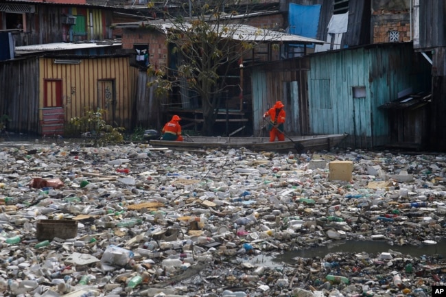 FILE - City workers remove garbage floating on the Negro River, which has a rising water level due to rain, in Manaus, Amazonas state, Brazil, June 6, 2022. (AP Photo/Edmar Barros, File)