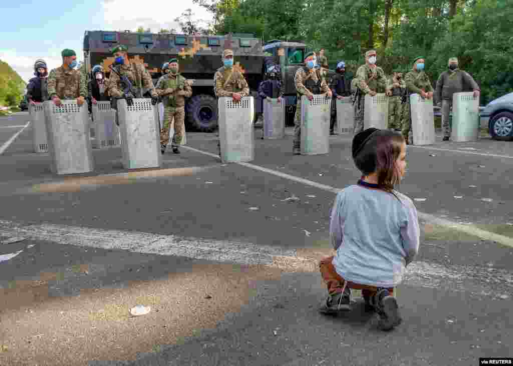 A Jewish pilgrim, who plans to enter Ukraine from Belaru for a pilgrimage, kneels in front of Ukrainian service members near Novi Yarylovychi crossing point in Chernihiv Region, Ukraine, Sept. 15, 2020. (Credit: BelaPAN)
