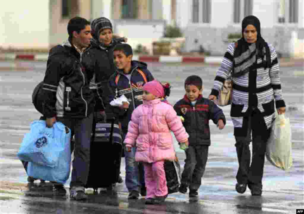 Members of a Tunisian family carry their belongings after they fled from Libya, at the Tunisia-Libya border near the village of Ras Ajdir, Tunisia, Wednesday, Feb. 23, 2011. (AP Photo/Lefteris Pitarakis)