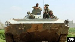 Para anggota pasukan pro-pemerintah Suriah mengendarai tank di Afris, Ghouta Timur, 10 Maret 2018.