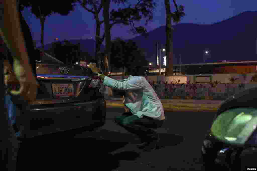 El doctor Carlos Martínez descansa mientras espera en la fila para obtener combustible, una demora que a veces se prolonga durante horas.