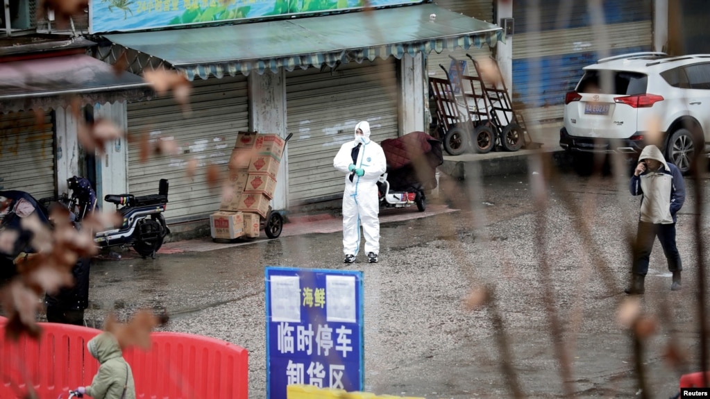 FILE - A worker in a protective suit is seen at a shuttered seafood market during the early spread of the coronavirus, in Wuhan, Hubei province, China Jan. 10, 2020.