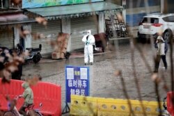 FILE - A worker in a protective suit is seen at a shuttered seafood market during the early spread of the coronavirus, in Wuhan, Hubei province, China, Jan. 10, 2020.