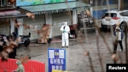 FILE - A worker in a protective suit is seen at a shuttered seafood market during the early spread of the coronavirus, in Wuhan, Hubei province, China Jan. 10, 2020.