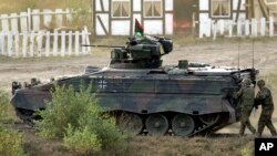 ARCHIVO - Varios soldados avanzan caminando junto a un vehículo de combate de infantería Marder durante una demostración realizada para la prensa en Bergen, cerca de Hannover, Alemania, en septiembre de 2011.