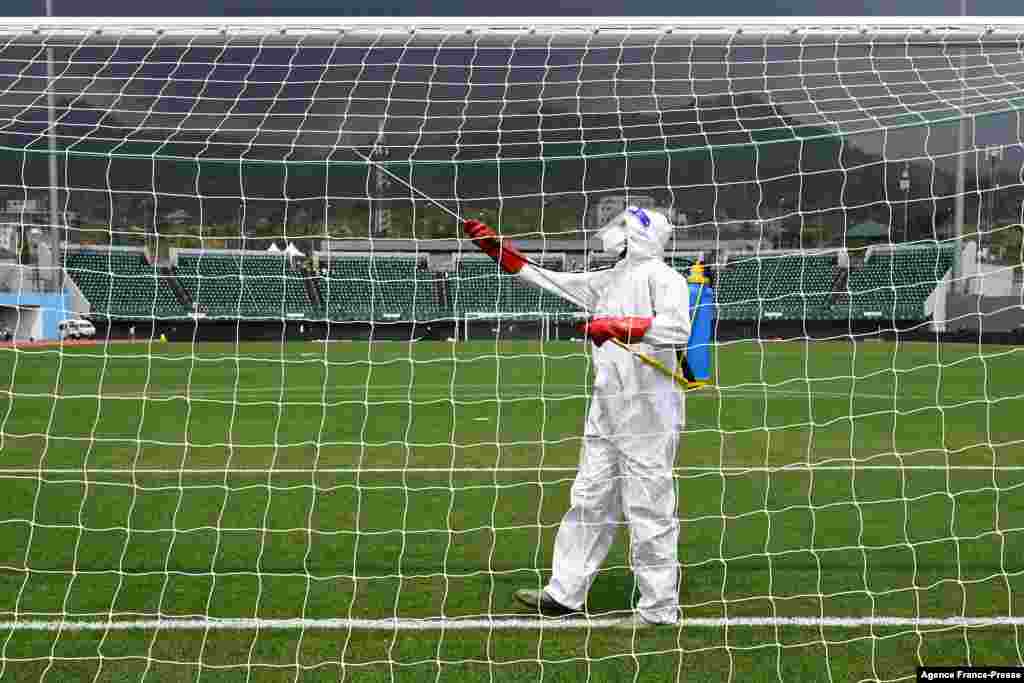 A worker sanitizes the goal posts ahead of the match between Tunisia and Mali at Limbe Omnisport Stadium in Limbe.