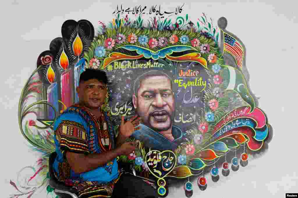 Pakistani truck-art painter Haider Ali, gestures as he speaks with Reuters next to a mural he painted, depicting George Floyd, in Karachi, Pakistan, June 12, 2020.