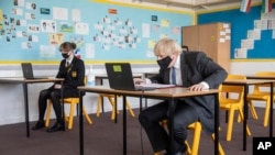 Britain's Prime Minister Boris Johnson visit Sedgehill School in south east London, Feb. 23, 2021, announced a gradual easing of one of Europe’s strictest lockdowns on, saying people will be able to meet a friend for coffee in a park in two weeks’ time.