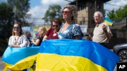 Supporters hold Ukrainian flags ahead of the arrival of President Volodymyr Zelenskyy's motorcade at the Scranton Army Ammunition Plant in Scranton, Pennsylvania, Sept. 22, 2024.