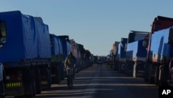Un ciclista pasa junto a camiones de carga atascados en Desaguadero, Bolivia, en la frontera con Perú, sin poder cruzar debido a los bloqueos de carreteras por las protestas antigubernamentales en Perú, el viernes 13 de enero de 2023. 