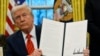 President Donald Trump holds up an executive order relating to the Foreign Corrupt Practices Act in the Oval Office at the White House, Feb. 10, 2025, in Washington.