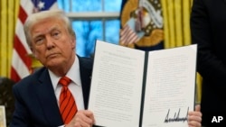 President Donald Trump holds up an executive order relating to the Foreign Corrupt Practices Act in the Oval Office at the White House, Feb. 10, 2025, in Washington.